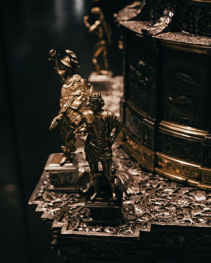 Close-up of an intricately detailed bronze and silver figurine on a metallic base, showcasing metalwork artistry.