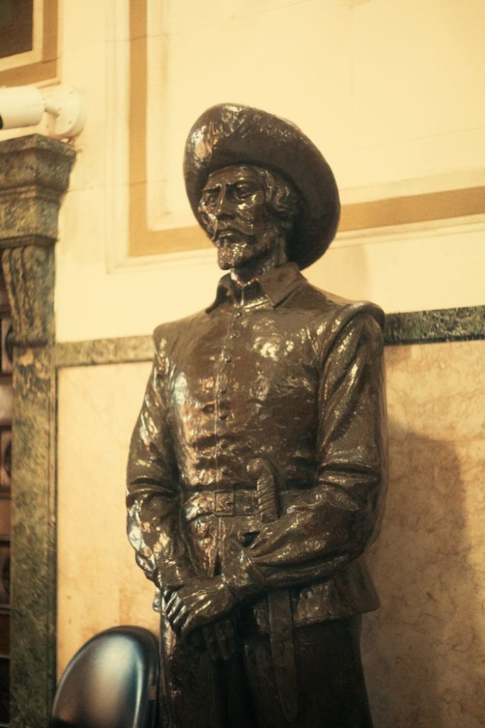 Mastering the First Impression: Your intriguing post title goes here A bronze statue of a historic figure wearing a hat and coat indoors with classic architecture.